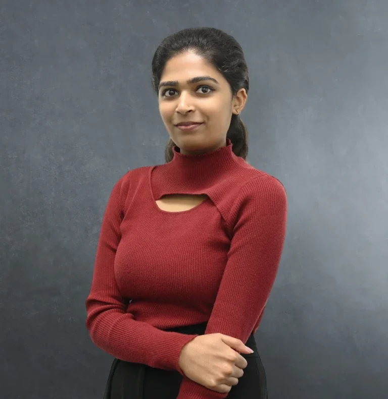 Krishnapriya Sivan, Paralegal at Axis Solicitors in Ilford London, wearing a burgundy sweater, professional headshot against grey background.