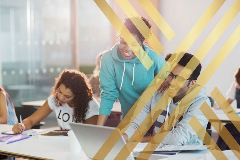 Students collaborating around a laptop in a classroom, illustrating employment opportunities and the Right to Work in the UK for Migrants through education, training, and career development.