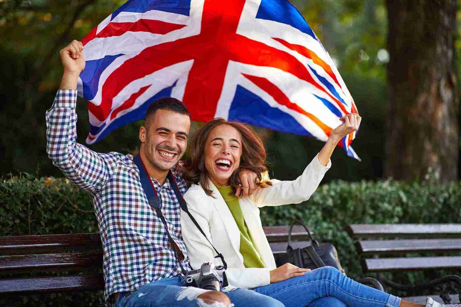 cheerful couple holding british flag in an urban