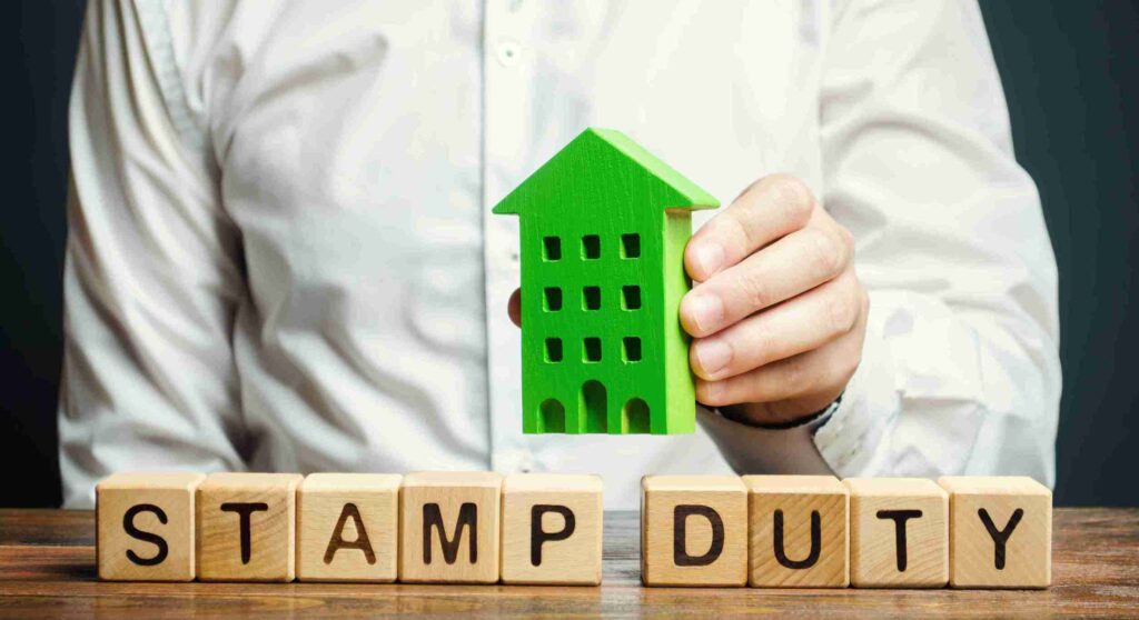 In the image it can bee seen a house is displayed along with a family indicating how stamp duty will affect your move. Changes in Stamp Duty UK 2025 How Does This Impact Your Move
