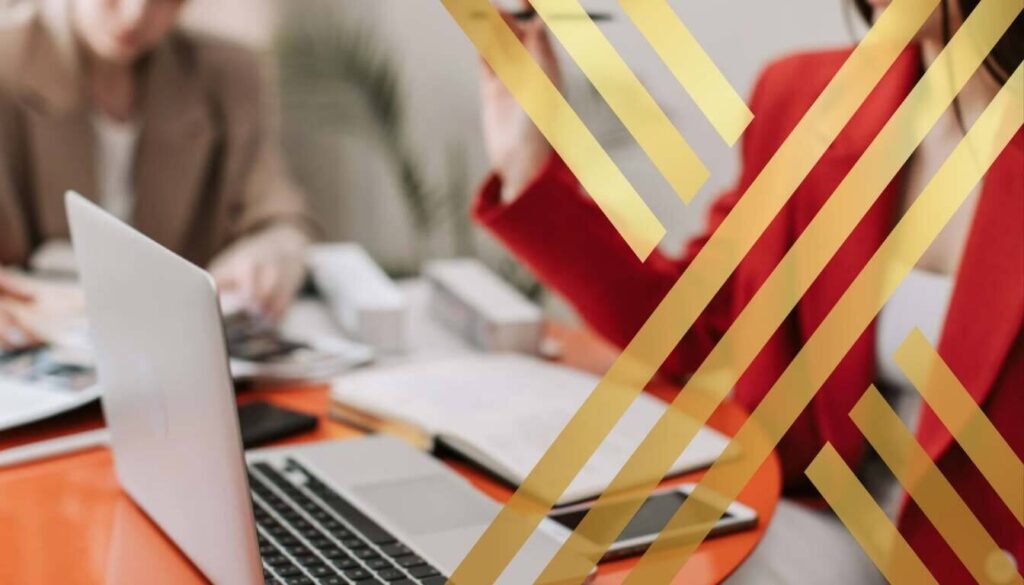 Blurred image of two professionals working on a laptop, representing high-skilled workers or planning immigration strategy for ILR Eligibility