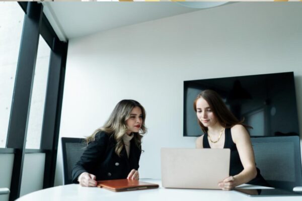 UK Visa Fees Explained: A Breakdown of Current Application Costs Two professional colleagues researching the ILR application fee and budgeting for UK immigration costs on a laptop.