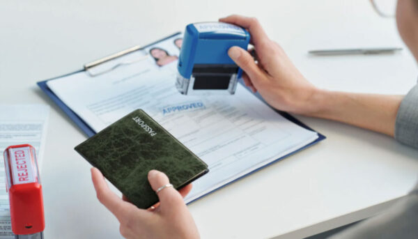 Complete Guide to Further Leave to Remain UK Visa Applications for Students A Home Office official using an approved stamp for a successful FLR visa extension in the UK.