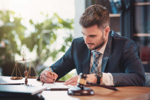 A lawyer reviewing defamation case documents with scales of justice and a gavel on his desk.