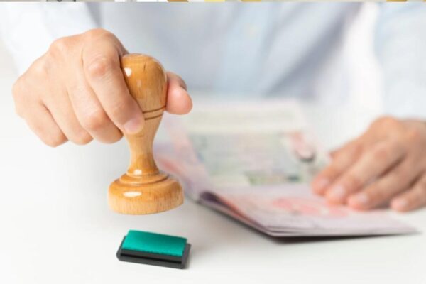 UK Visa Fees Explained: A Breakdown of Current Application Costs A hand stamping a passport, representing a successful application after paying the UK visitor visa fees and processing charges.