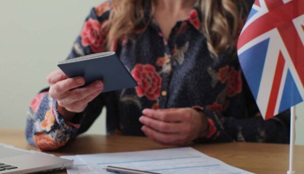 Woman holding passport and UK flag, representing a UK visa application.