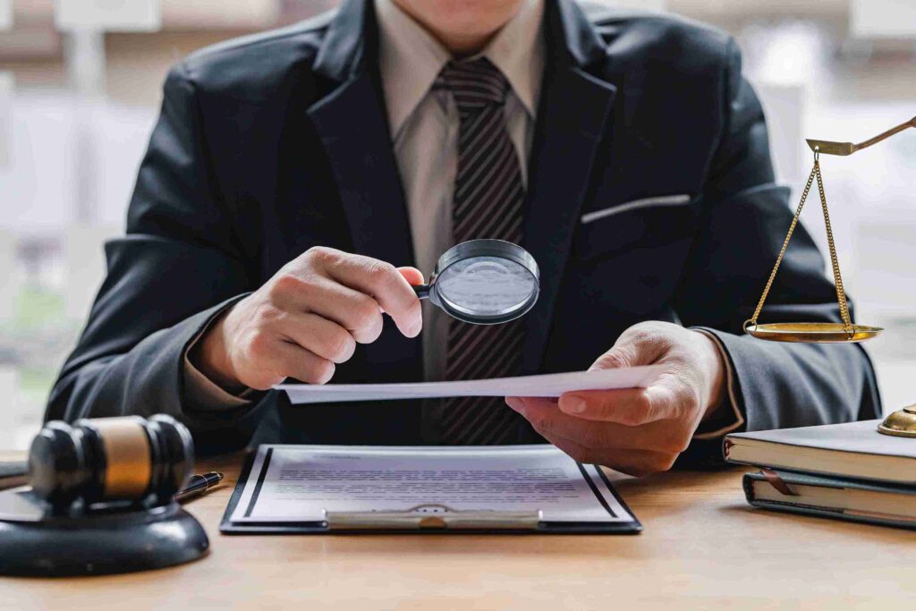 Person in suit examining document with magnifying glass, gavel, and scales, representing VAT investigations.