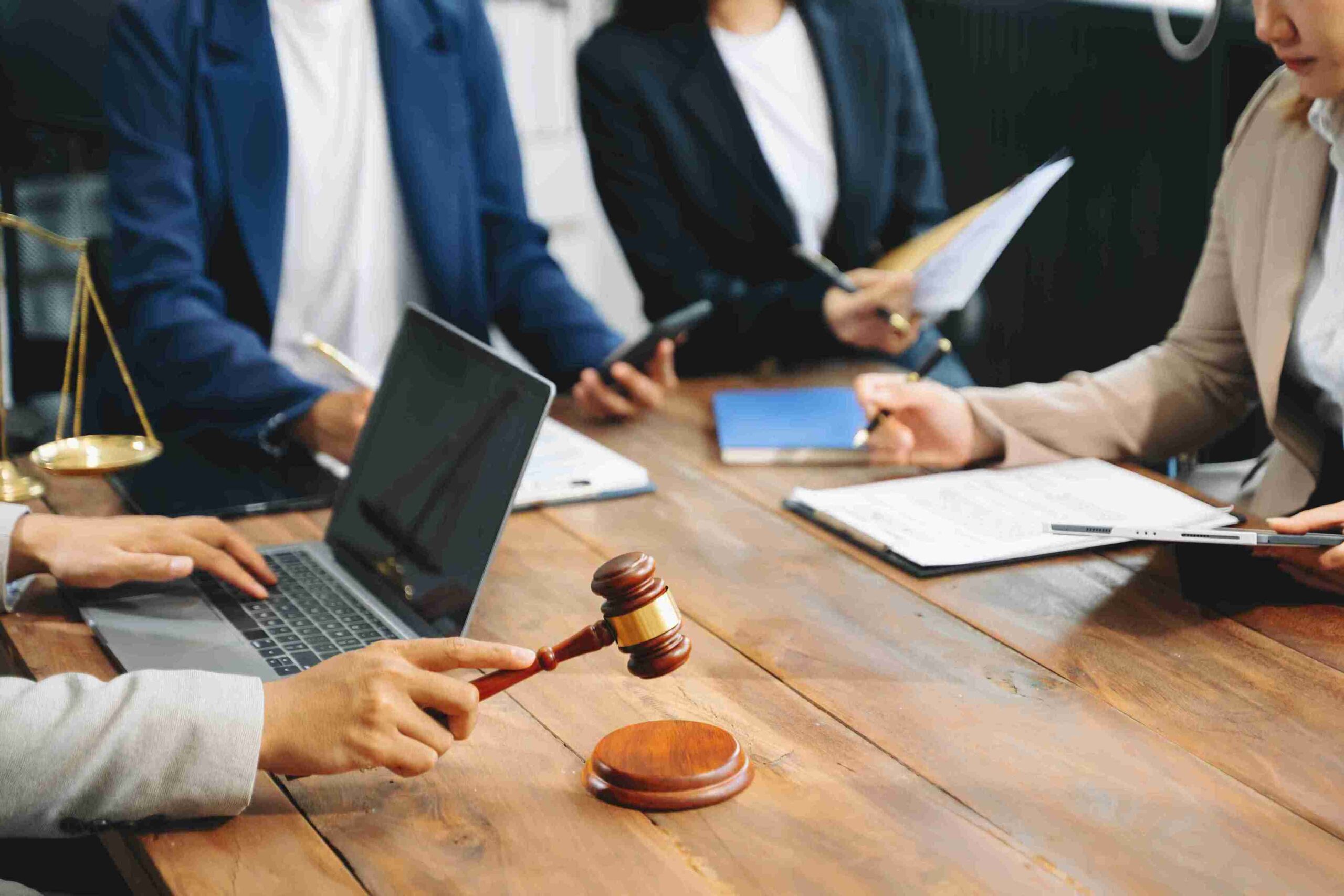 Professionals in suits at table with gavel, documents, laptop, and scales, representing HMRC tax investigations and experienced legal representation.
