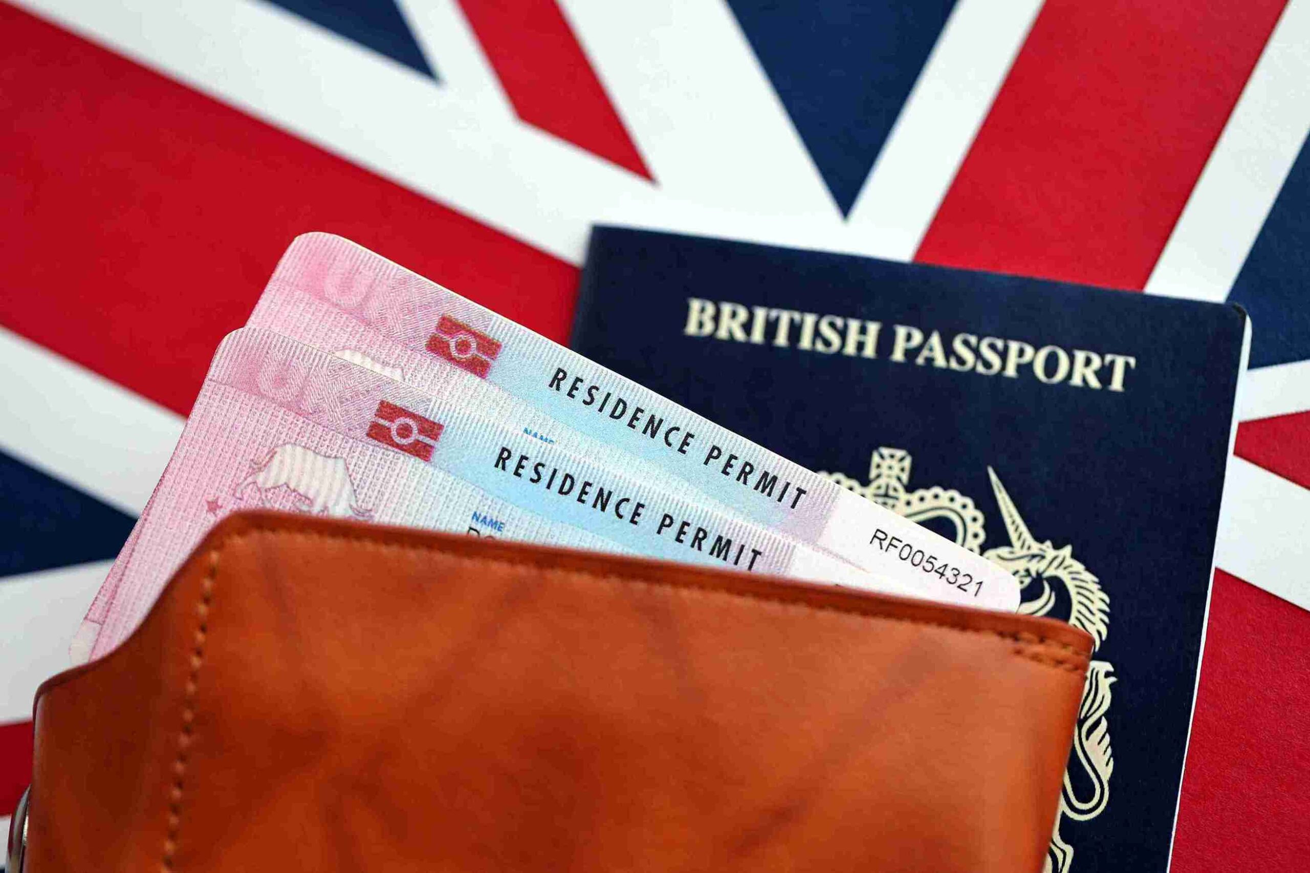 British passport and residence permits in wallet against blurred Union Jack, representing Indefinite Leave to Remain in the UK for permanent lawful settlement