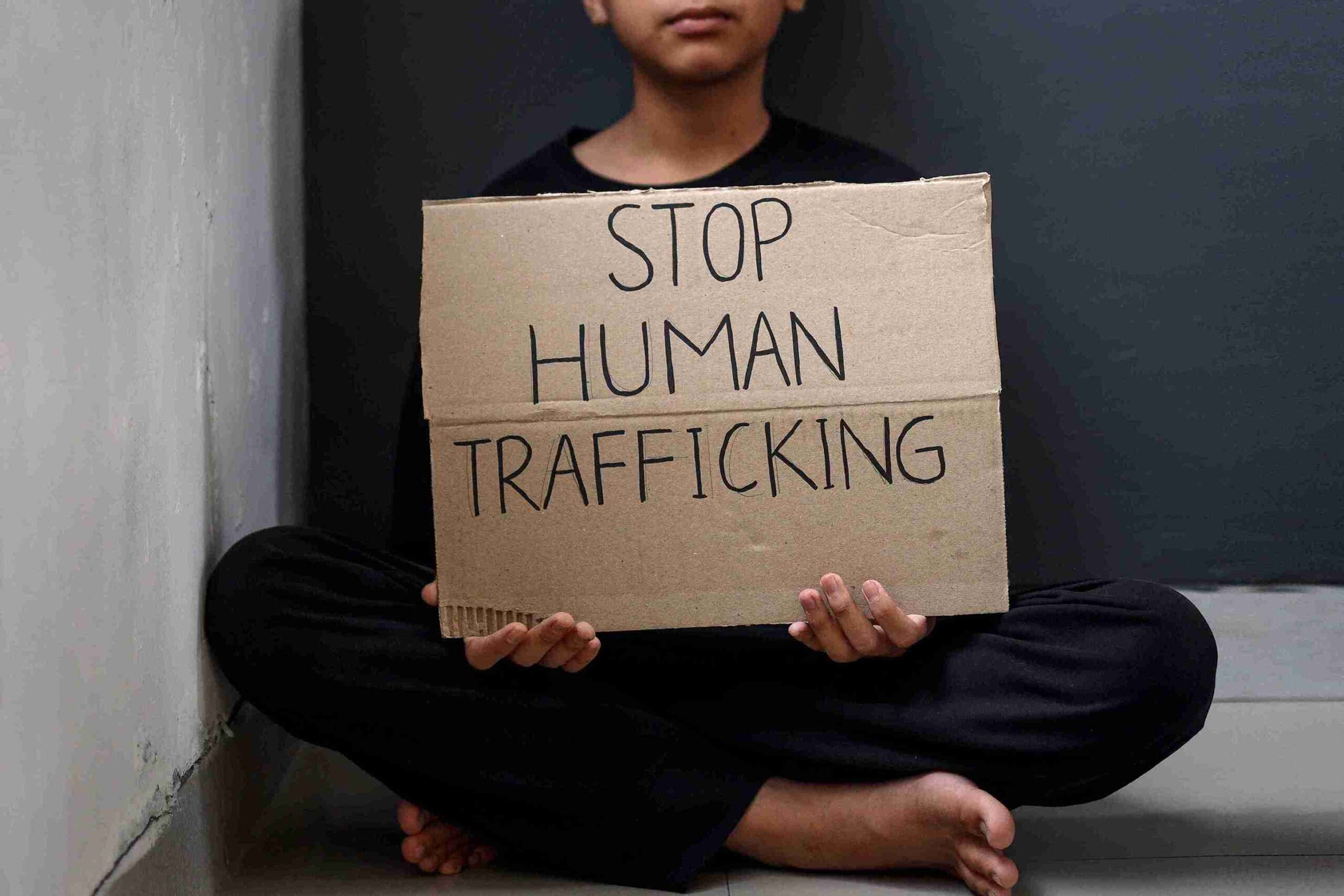 A person stands holding a sign that reads "Stop Human Trafficking," advocating for awareness and action against this issue.