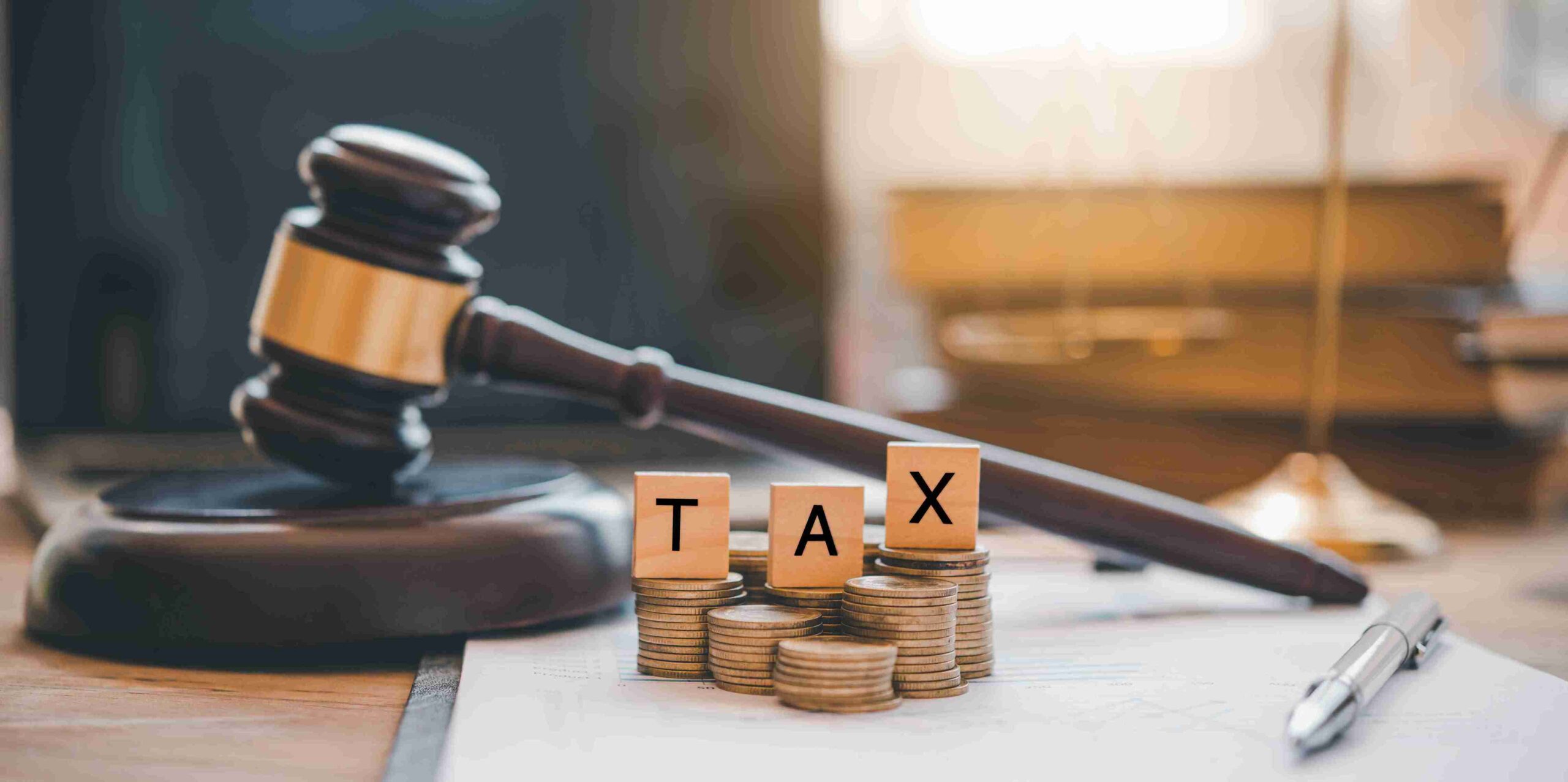 Gavel beside stacked coins and 'TAX' blocks, representing PAYE investigations and legal financial review.