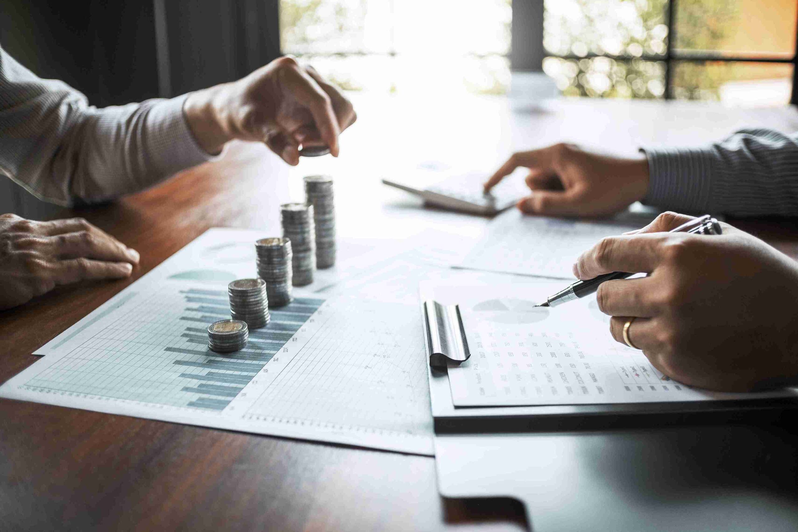 Hands arranging coin stacks on financial charts, representing financial settlements and property disputes with clear, multilingual legal support.