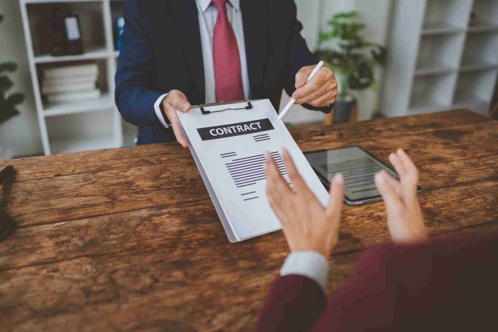 Formal desk meeting with contract and pen, representing expert guidance on sponsor licence retention, transfers, and corporate compliance.