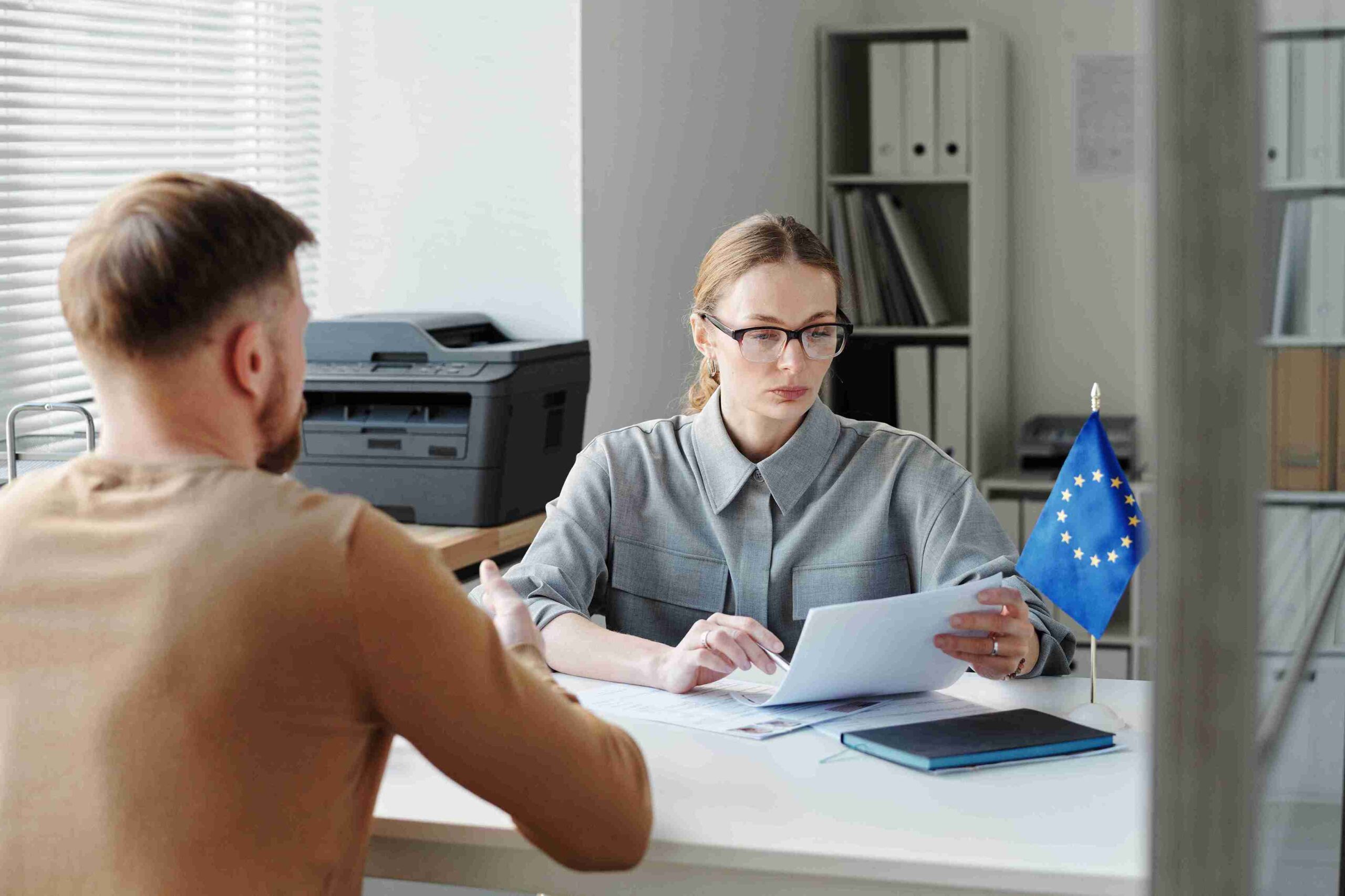 Woman at desk reading documents with EU flag, representing professional guidance for accurate Schengen visa applications and compliant European travel.