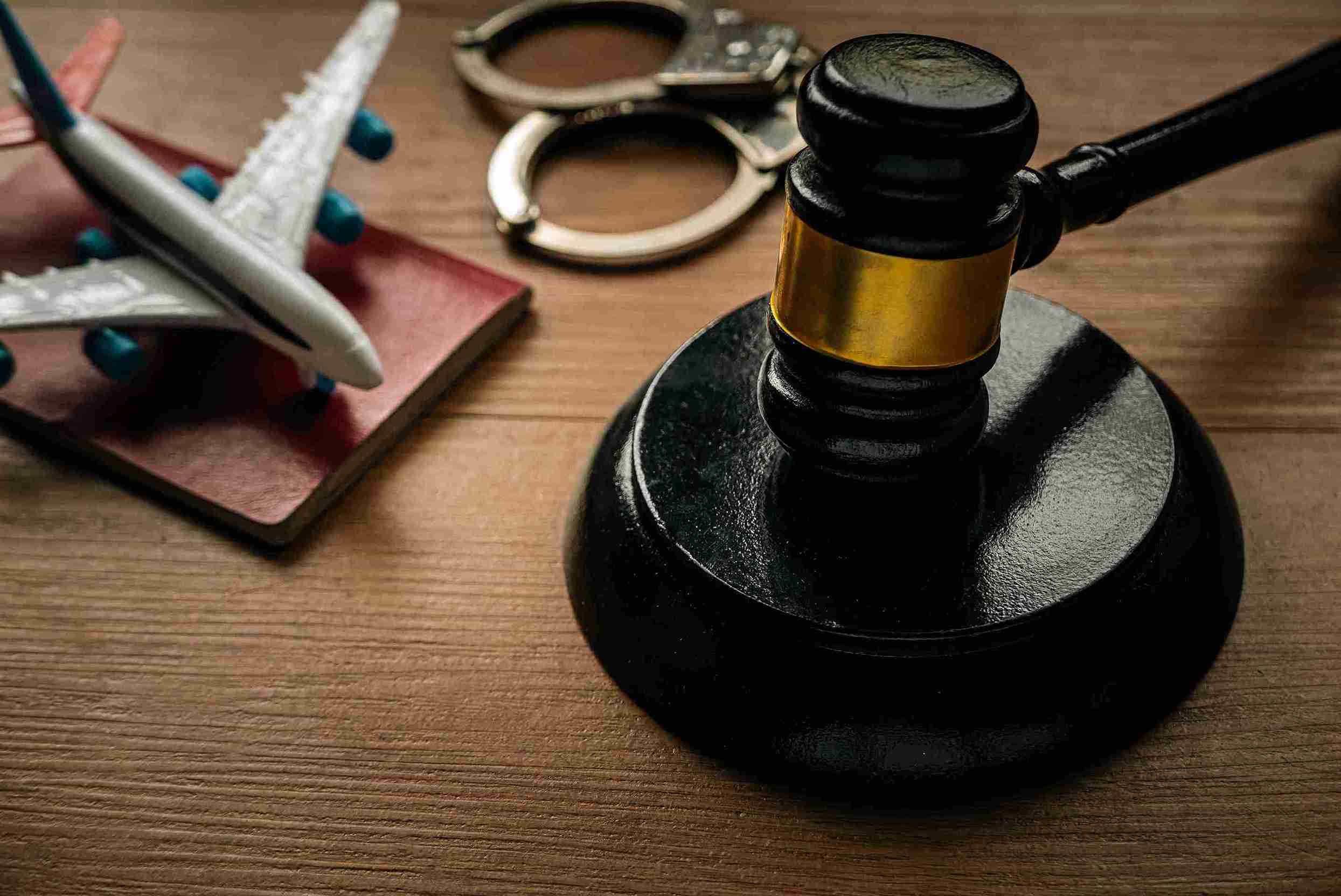 A judge's gavel and a toy airplane rest on a wooden table, symbolizing legal decisions and immigration challenges.
