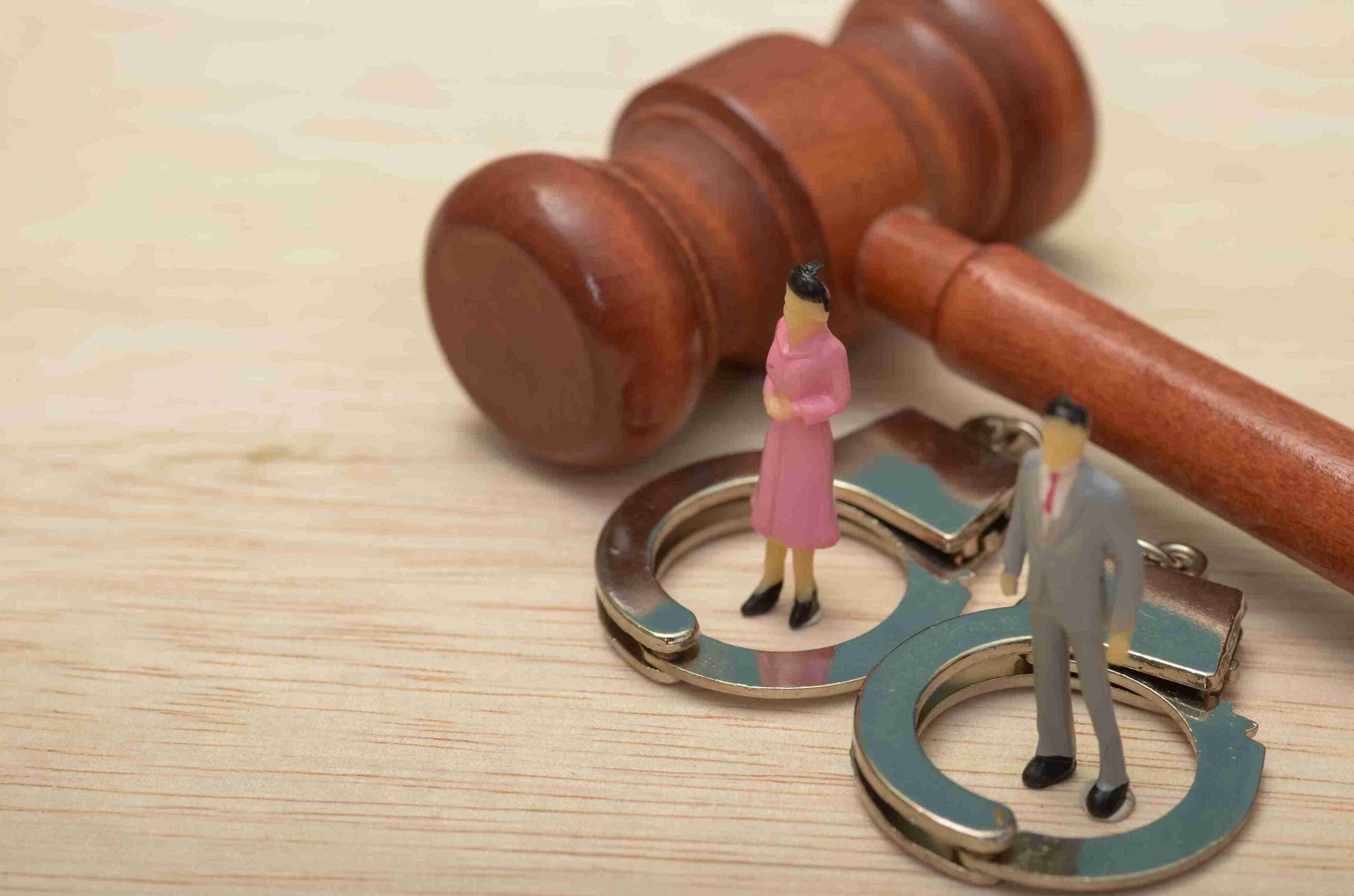 Gavel and handcuffs with miniature figures inside, representing non-molestation orders under family law.