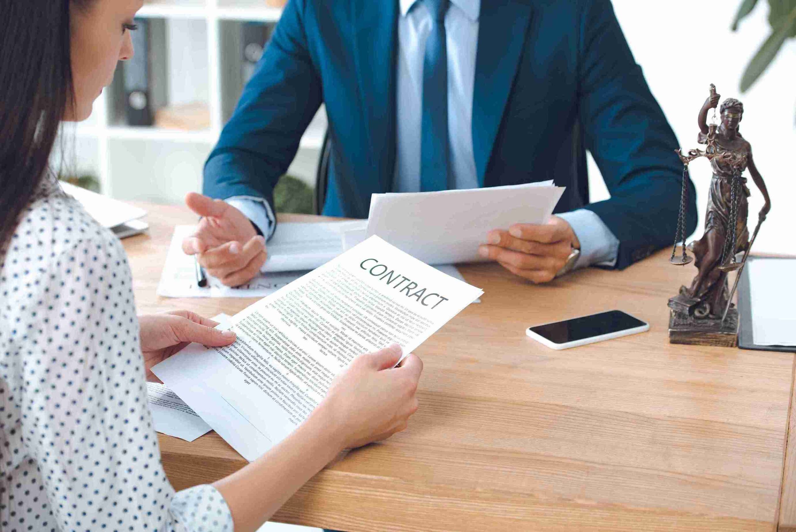 Woman and man reviewing contract at desk with Lady Justice statue, representing legal eligibility and financial remedy options under UK family law.