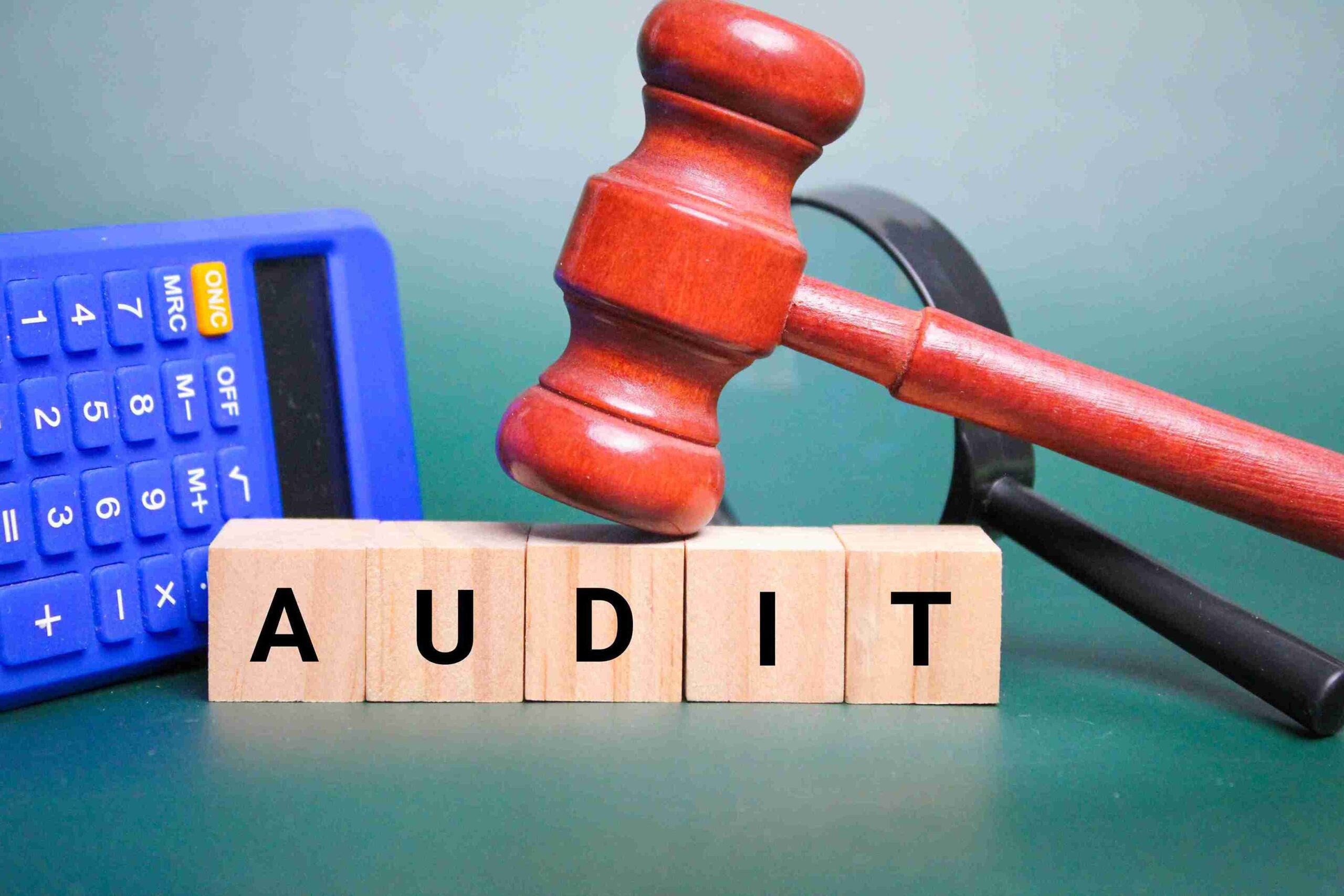 Gavel on ‘AUDIT’ blocks with calculator, representing HMRC disputes, tax investigations and reputational risk.