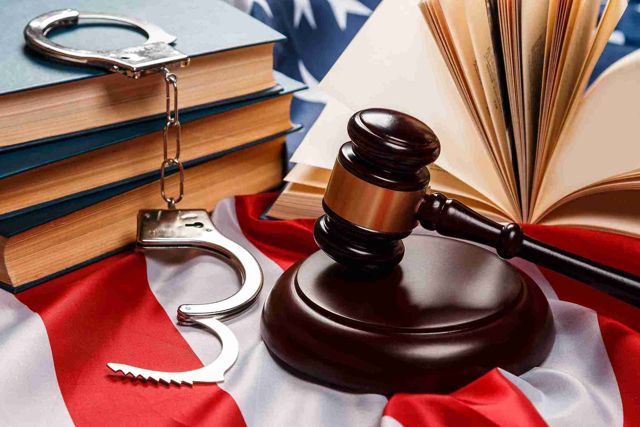 Gavel, law books, and handcuffs on flag, representing legal intervention to protect rights and release from detention.