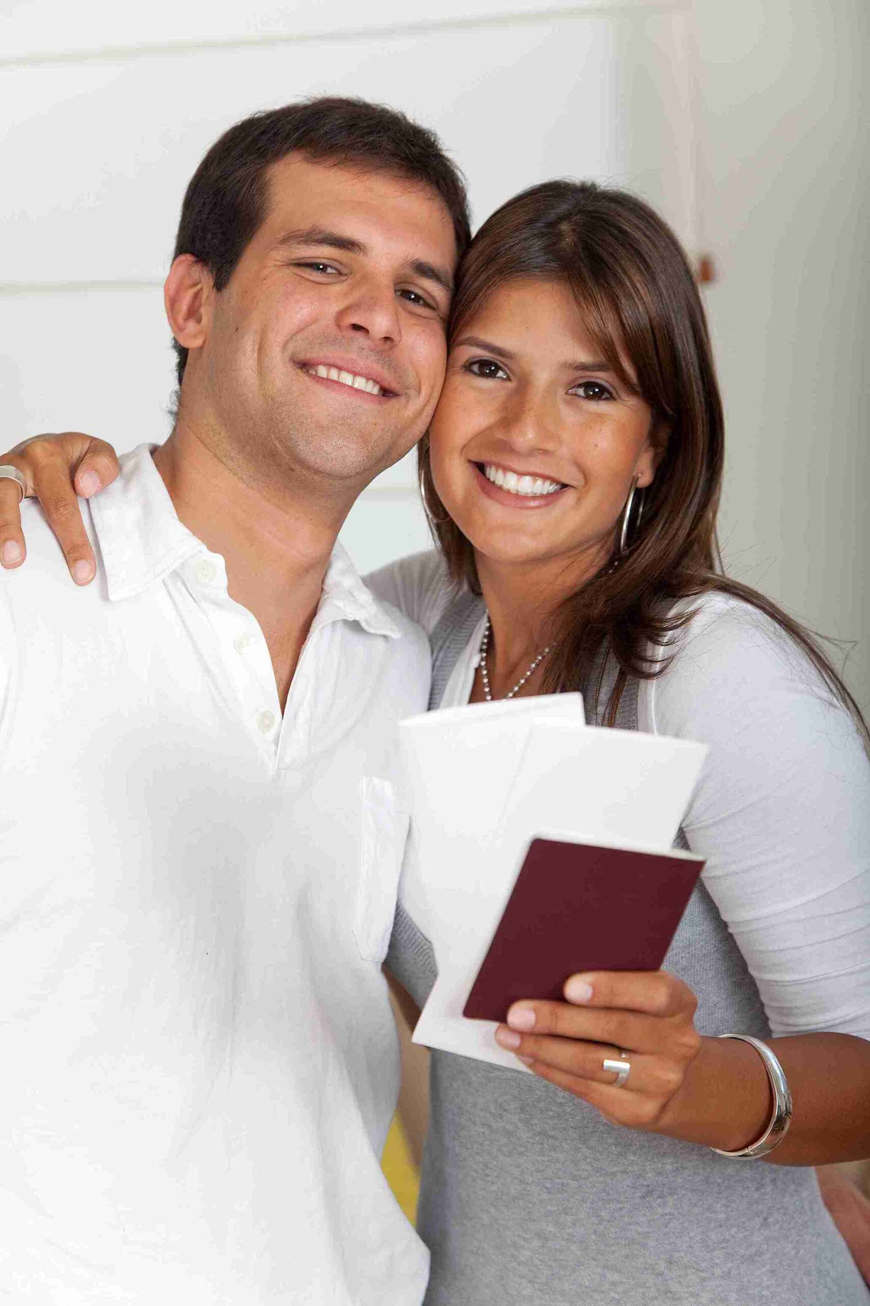 Smiling couple holding passport and travel documents, representing specialised legal support to extend a UK spouse visa and continue living together.