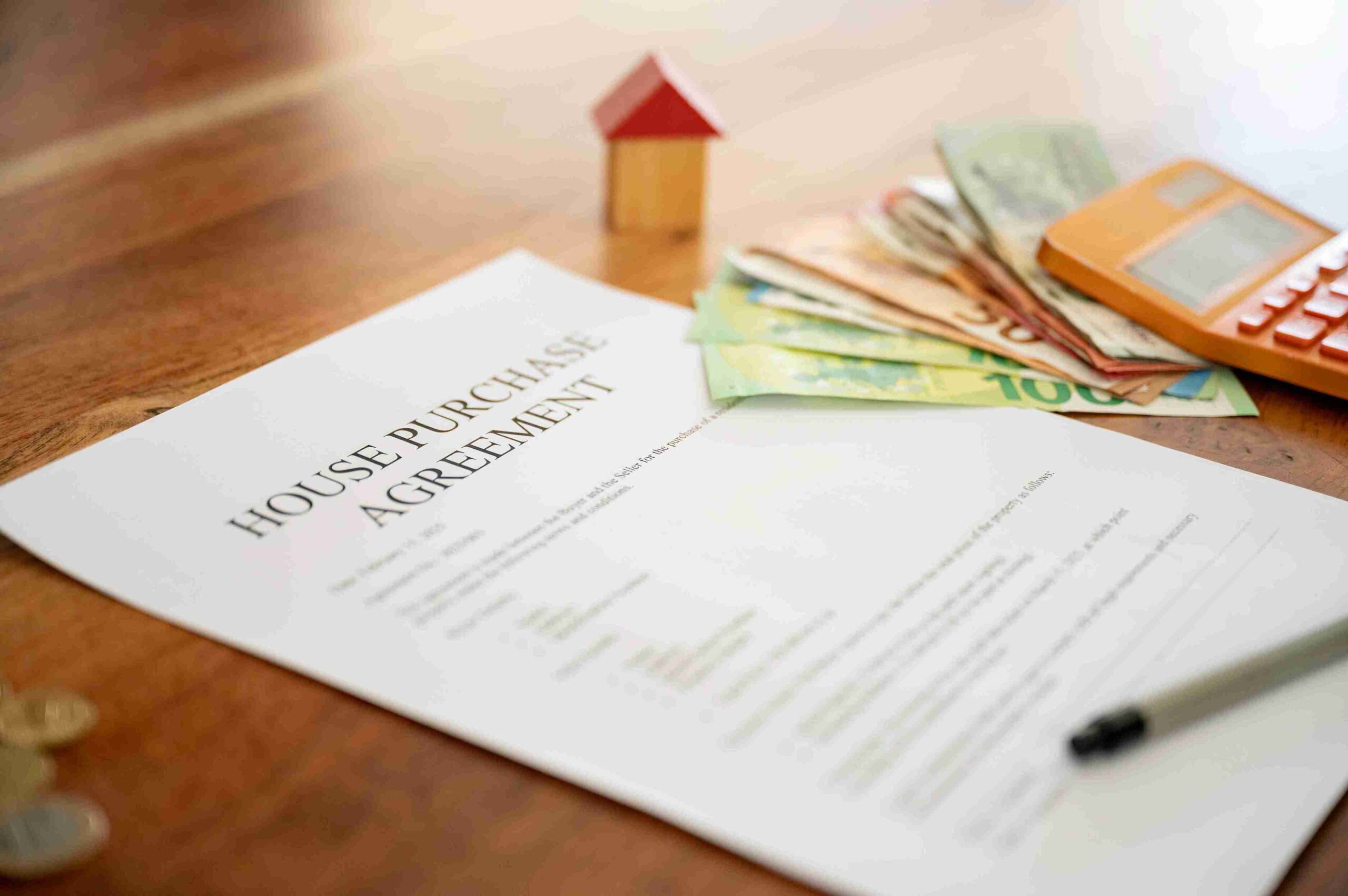 House purchase agreement with calculator, cash, and property model, representing financial settlement disputes.