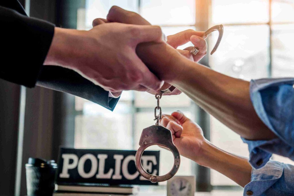 Police officer handcuffing a person in front of a "Police" sign, representing enforcement and legal consequences of non-molestation orders, including arrest.