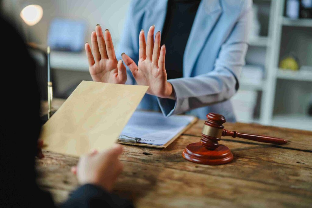 Person refusing document at desk with gavel, representing legal protection through restraining orders and domestic violence protection measures for long-term safety.