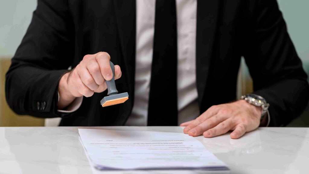 A man in a suit holds a rubber stamp above a document, approved to Work Refusal visa