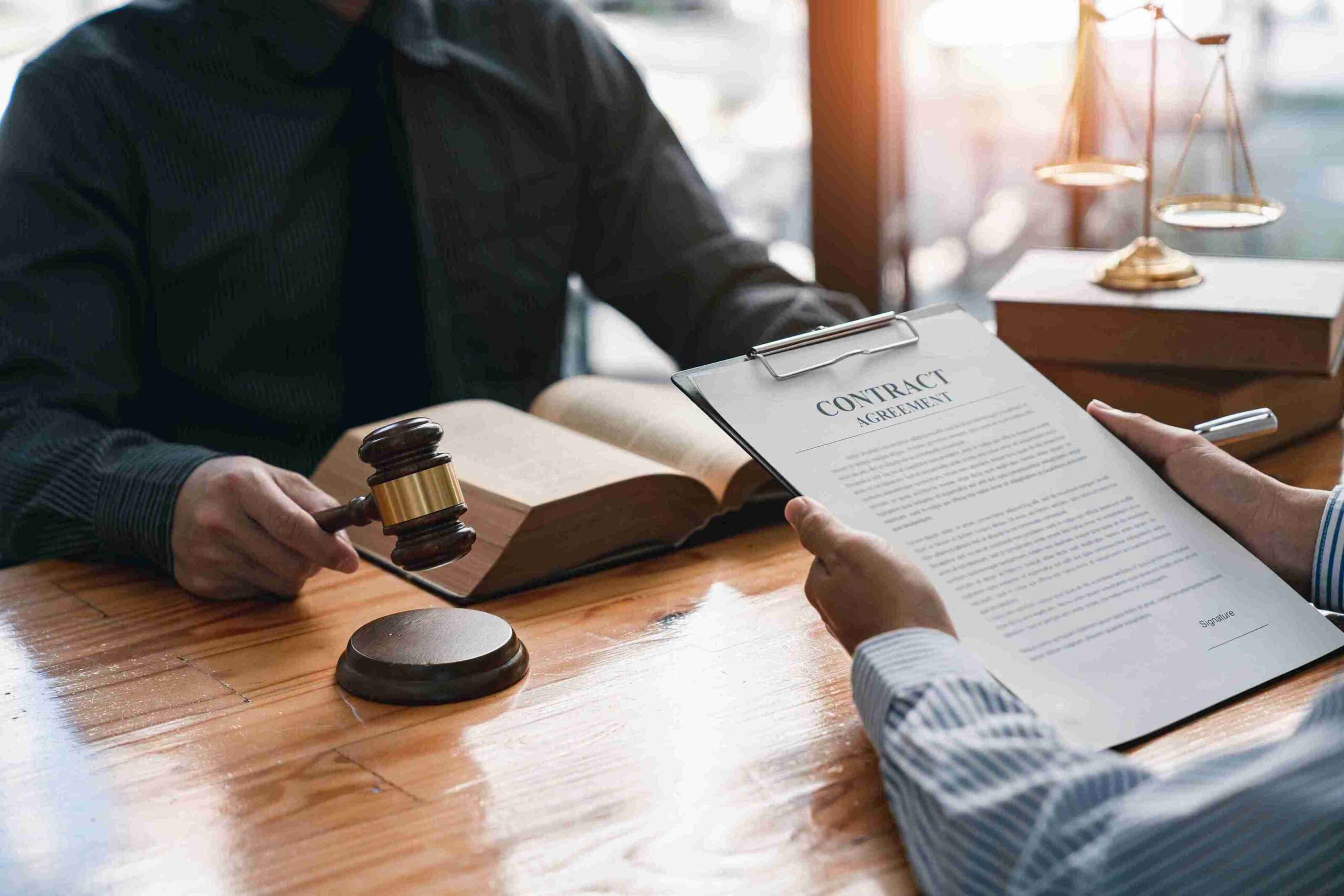 Two people at a table with gavel and legal books, representing detention assessment, bail applications, and client representation.