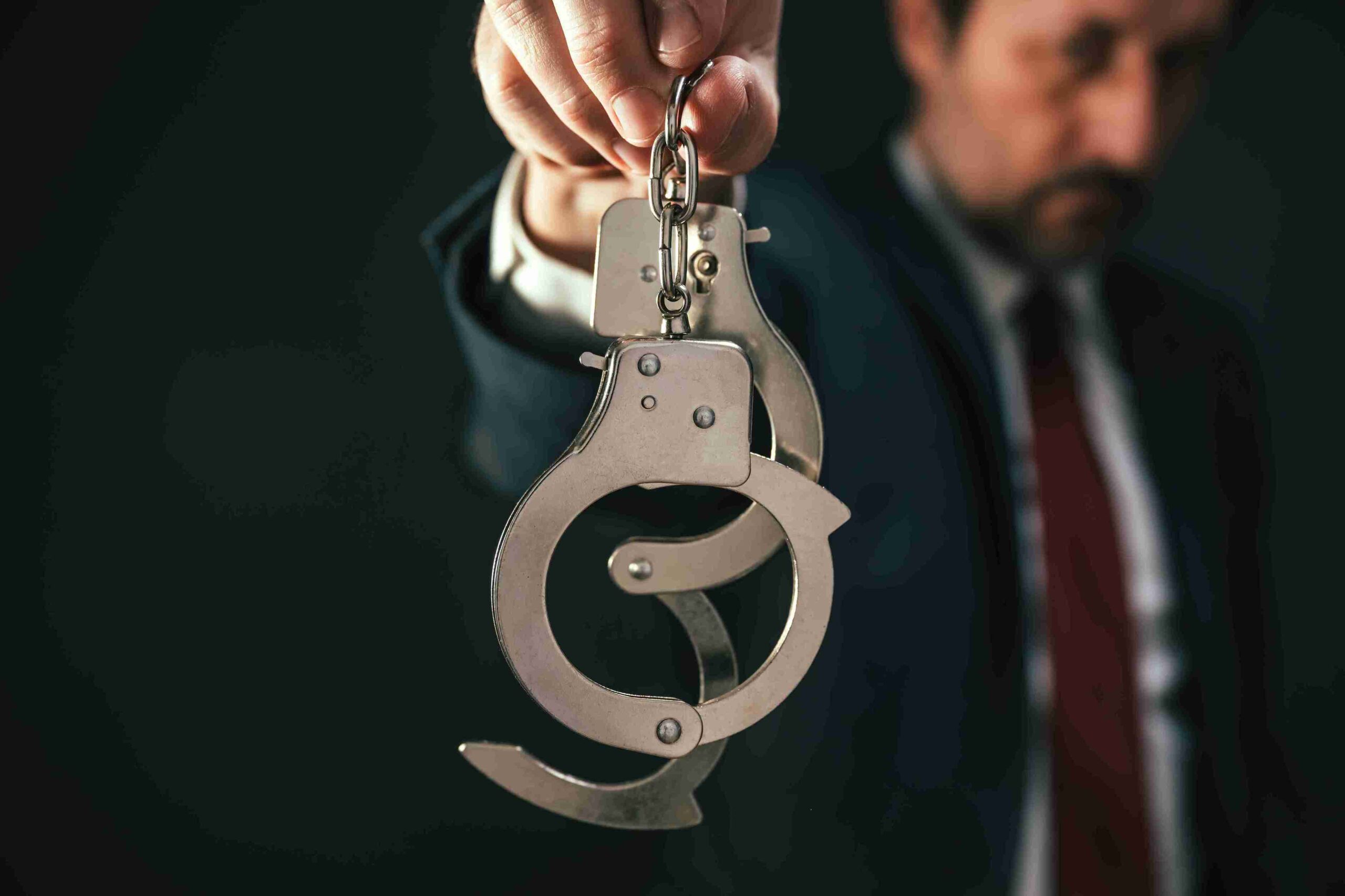 Person in suit holding handcuffs, representing specialist legal support to prevent deportation and secure release from UK immigration detention.