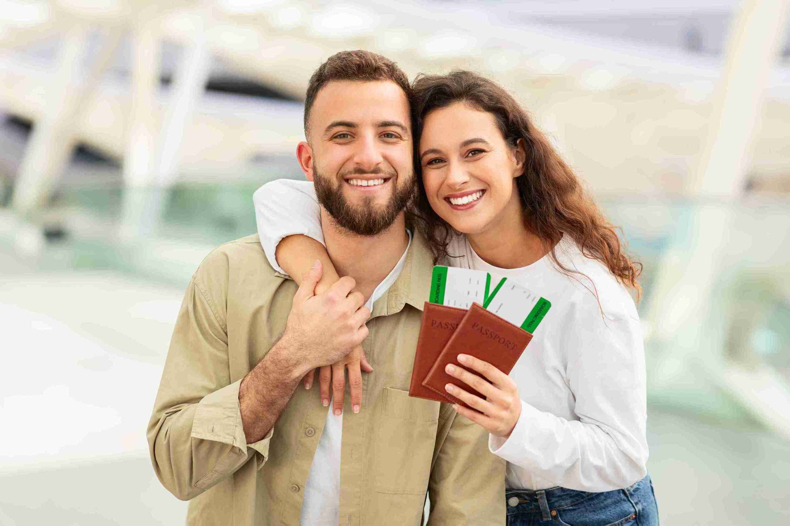 Cheerful couple at an airport holding passports and boarding passes, representing a successful spouse visa for travel and relocation.