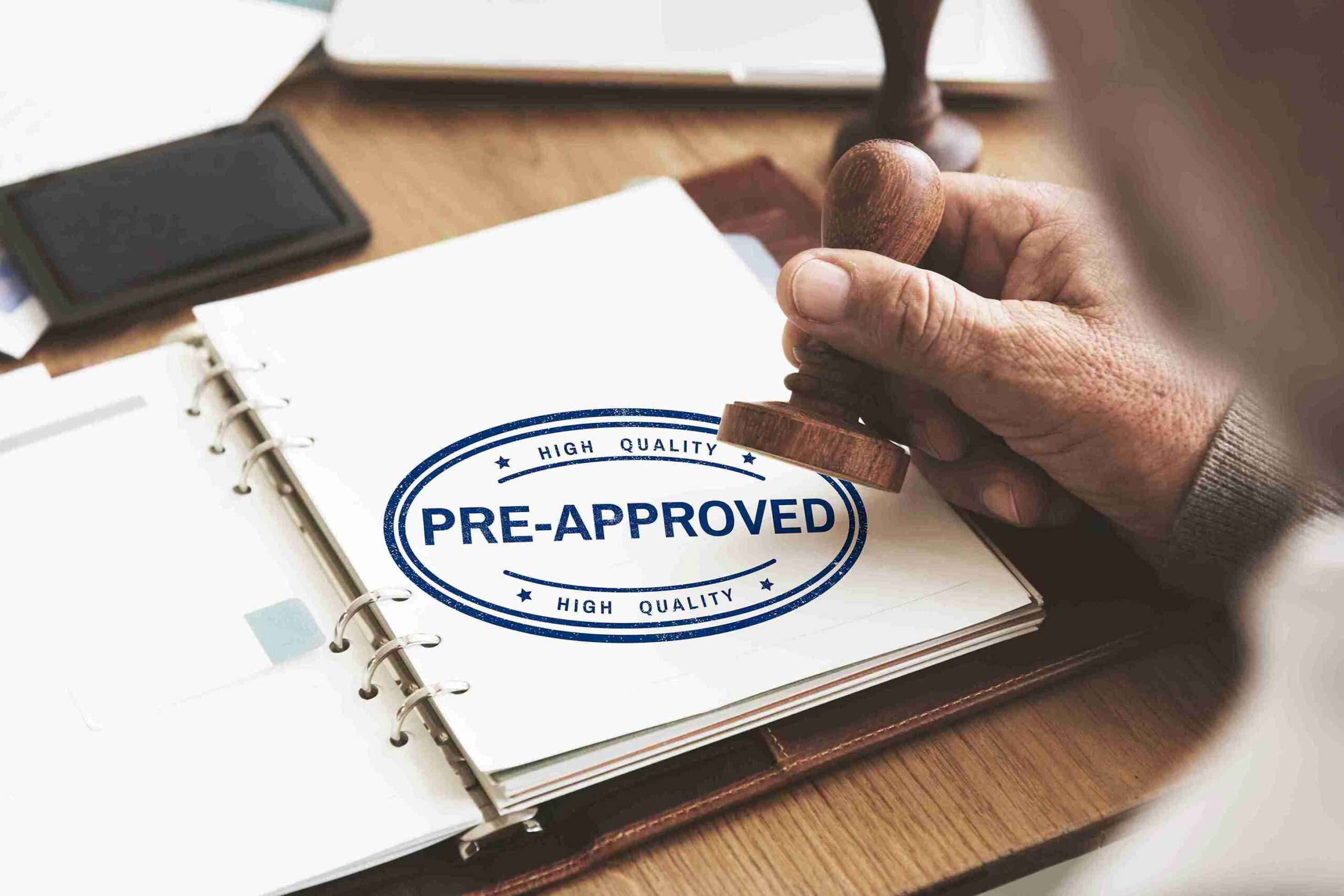 Hand stamping “PRE-APPROVED” on documents, representing applying for a UK spouse visa extension before current leave expires.