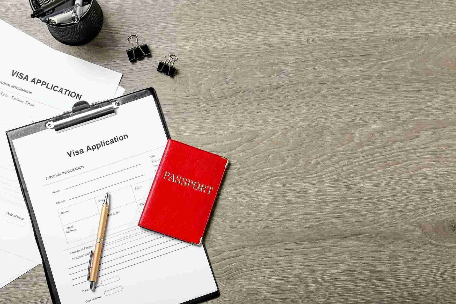 Visa application on clipboard with passport and pen, representing Solicitors guiding the UK spouse visa extension process.