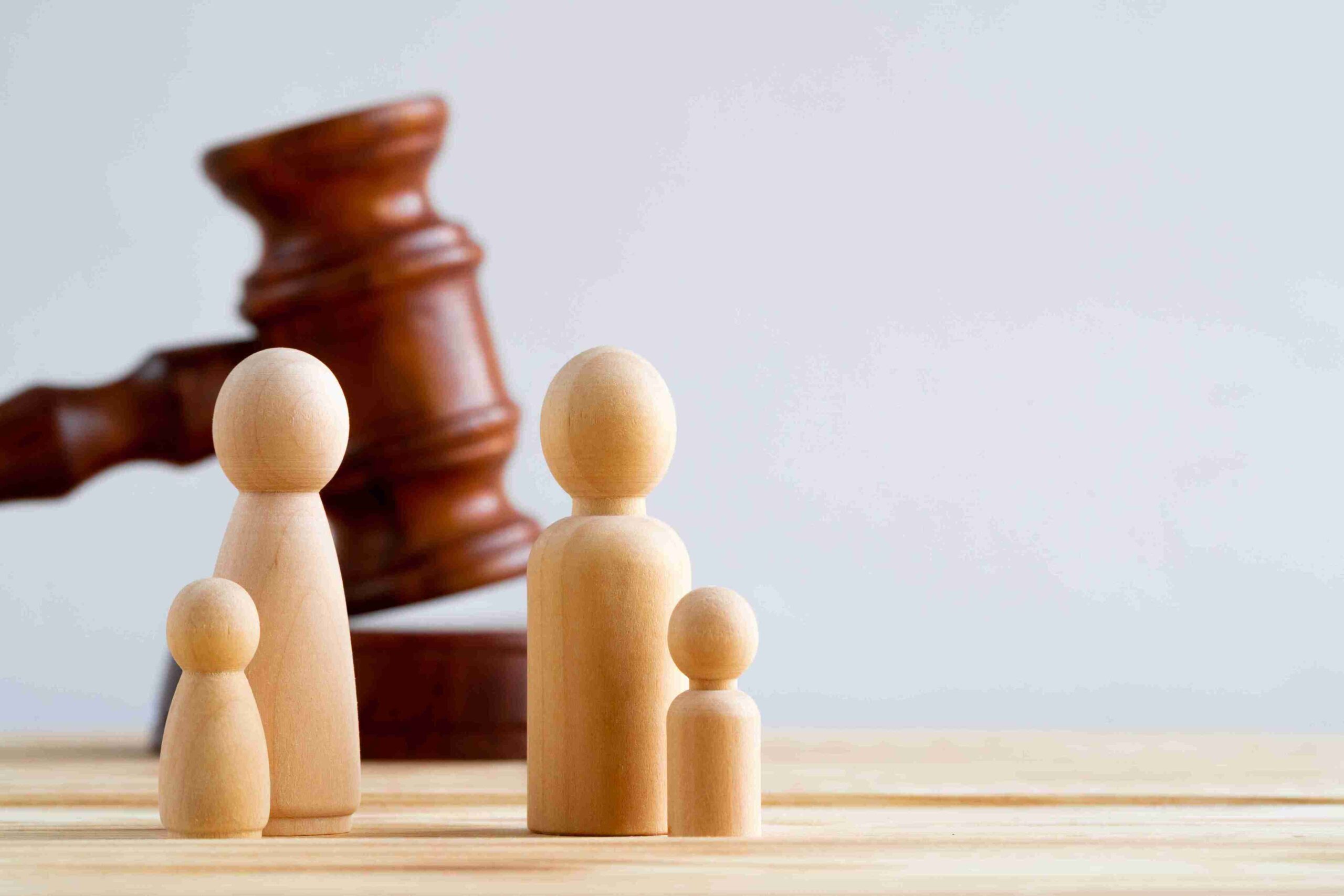 Wooden family figures with a gavel, representing clear and supportive legal guidance for applying for a family law injunction.