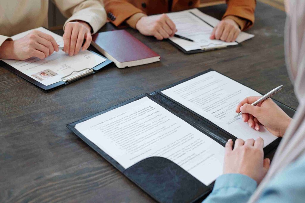 Man handing a clipboard with passport and UK document to woman, representing assessment of appeal rights, legal arguments, and evidence gathering.