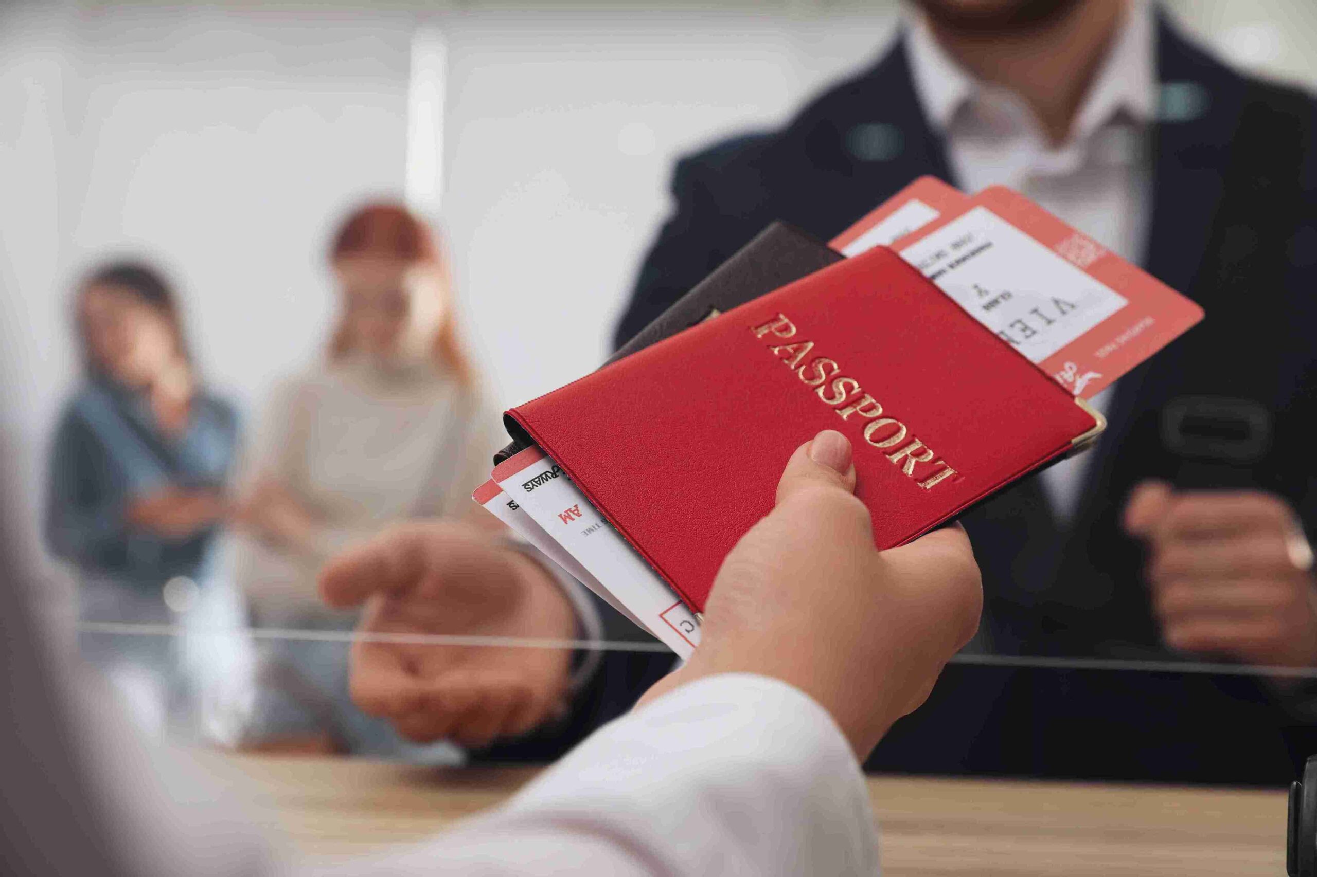 A person holding a standard passport and a red passport, ready for travel or identification purposes.