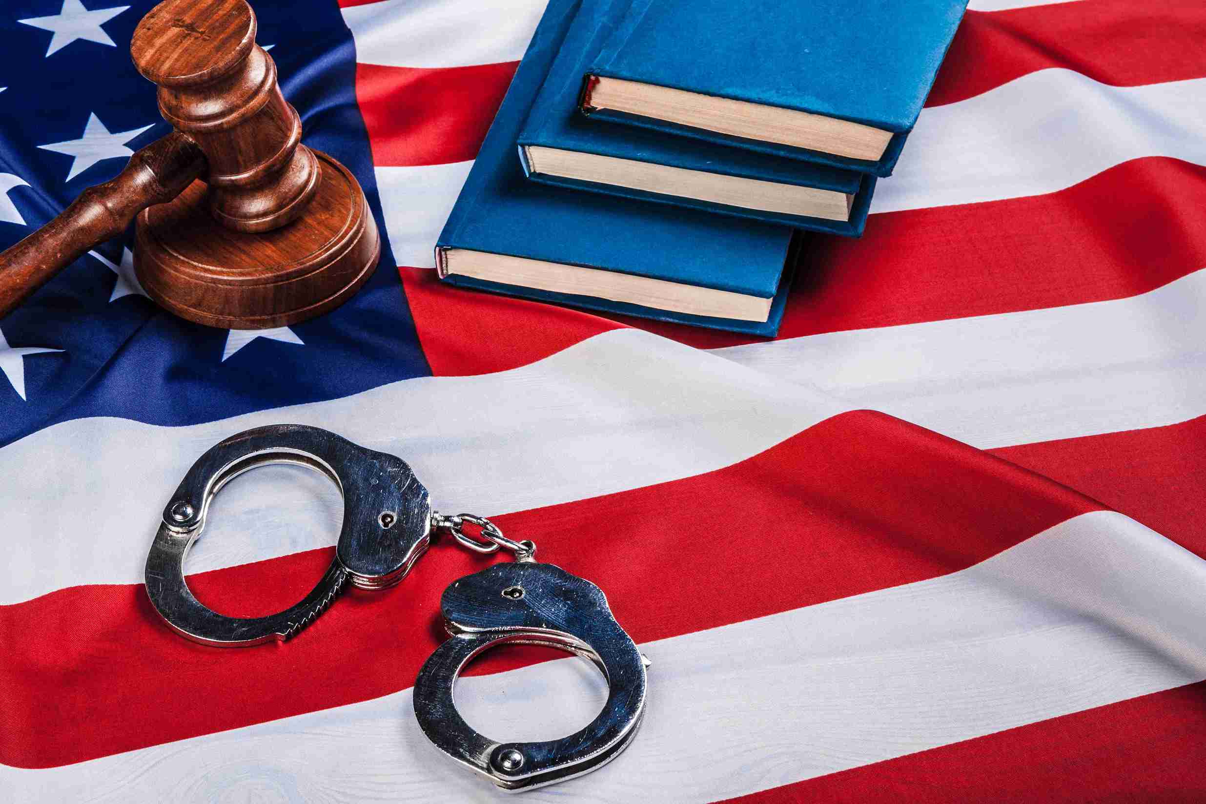 Handcuffs and a gavel rest on an American flag, symbolizing justice and law enforcement in the United States.