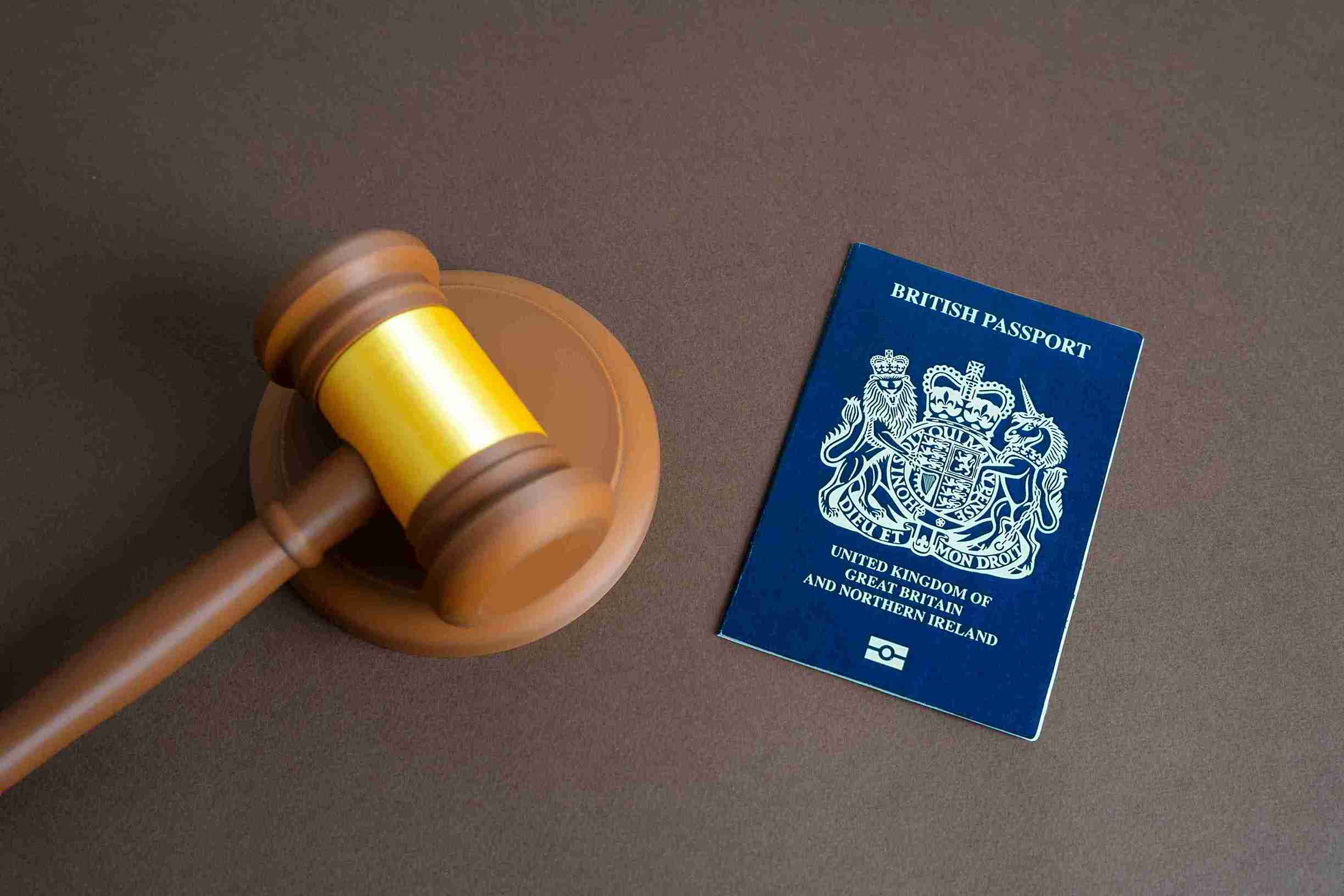 British passport resting beside a wooden gavel, symbolizing legal authority and travel documentation.