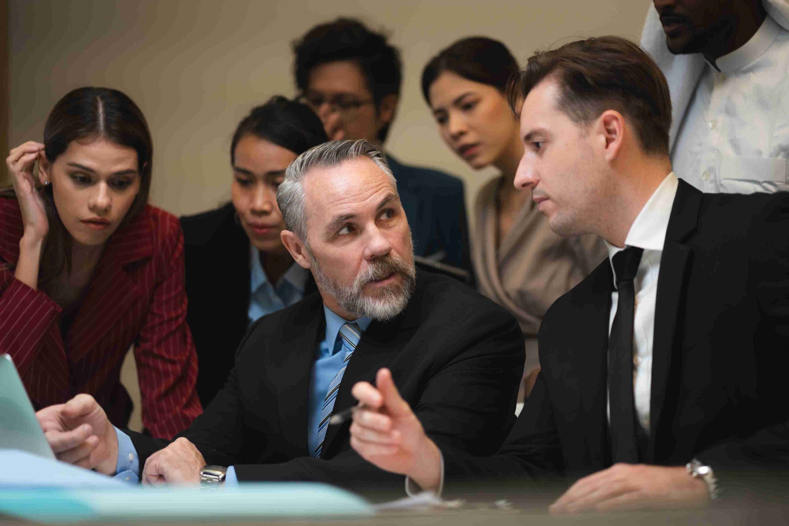 A diverse group of business professionals engaged in a meeting around a conference table, discussing ideas and strategies.