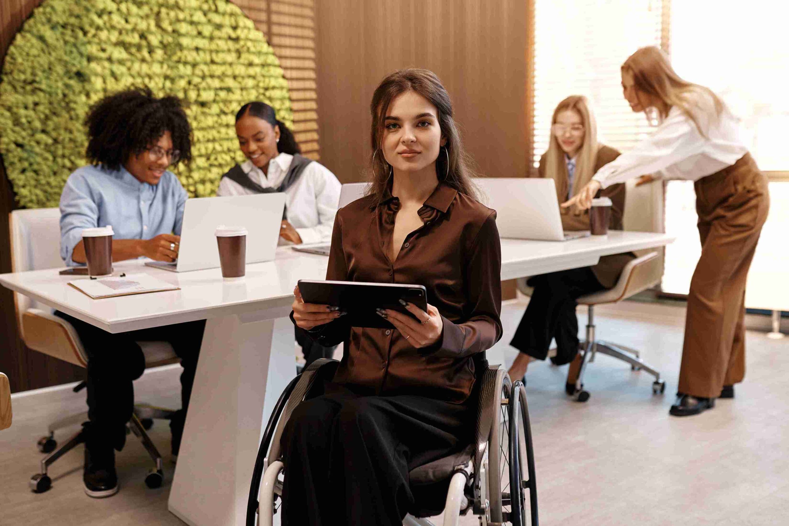 A woman in a wheelchair sits at a table, engaged in conversation with a group of people around her.
