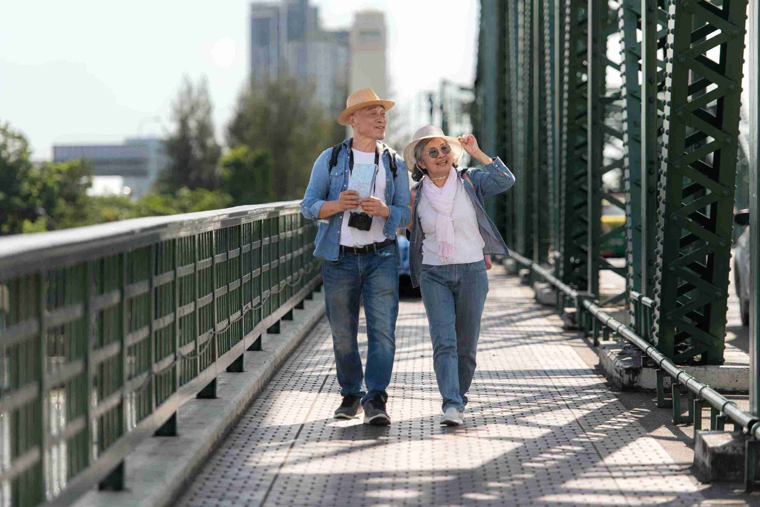 Senior couple walking hand in hand on a scenic bridge, enjoying a peaceful moment together outdoors.