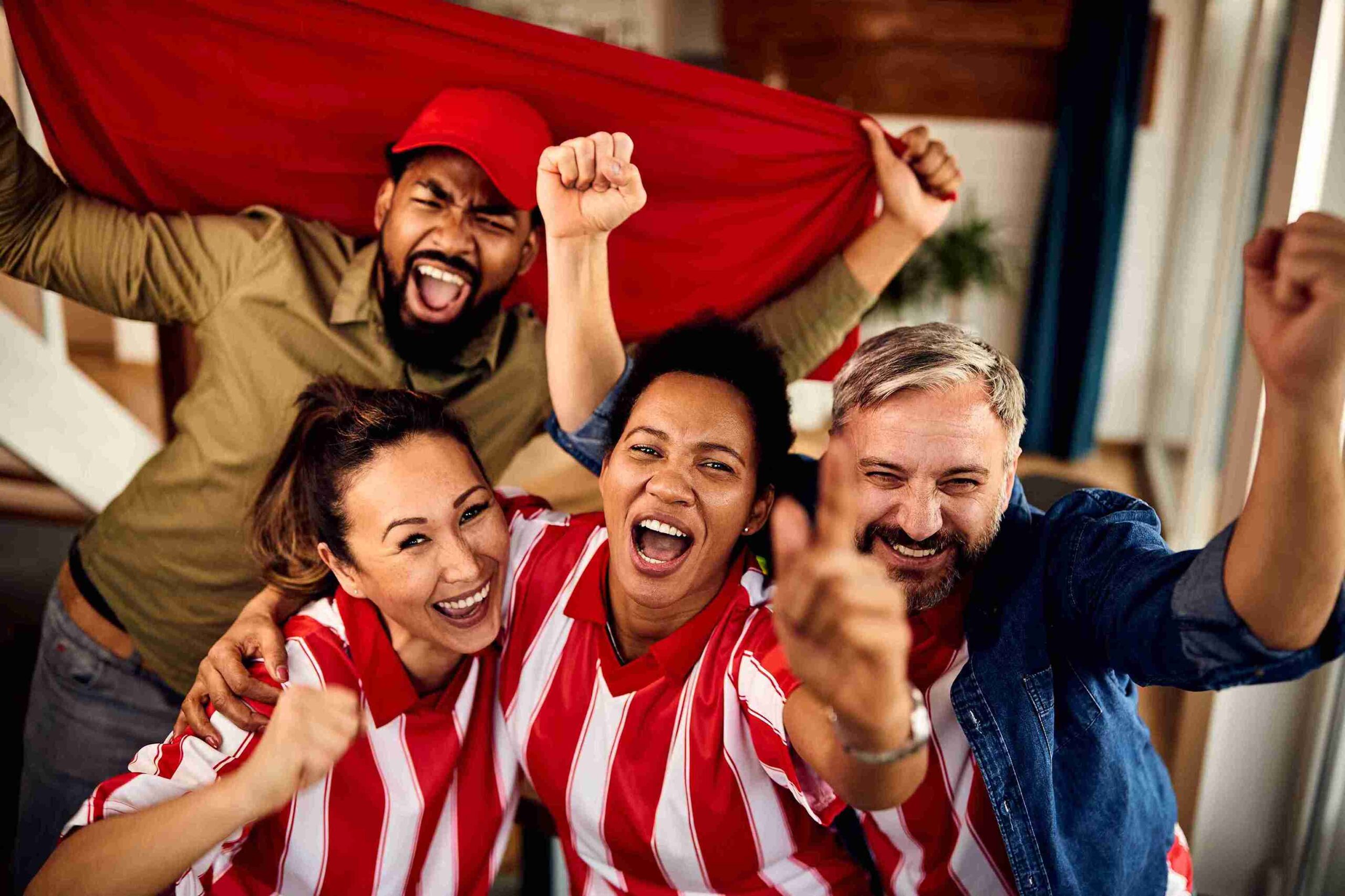 A lively group of people in red and white shirts enthusiastically cheering together at an event