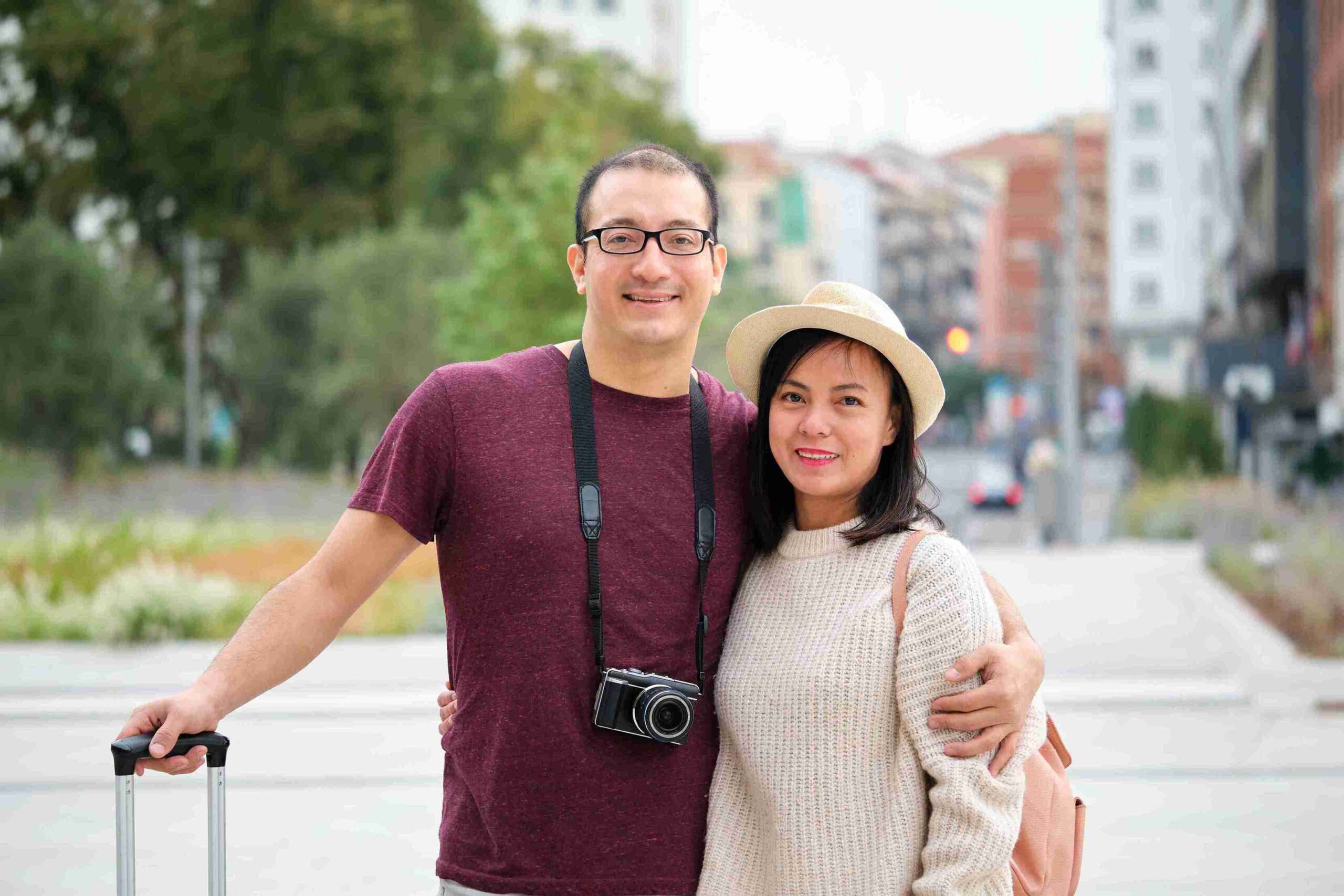 A man and woman stand beside a suitcase, smiling and ready for their journey together.