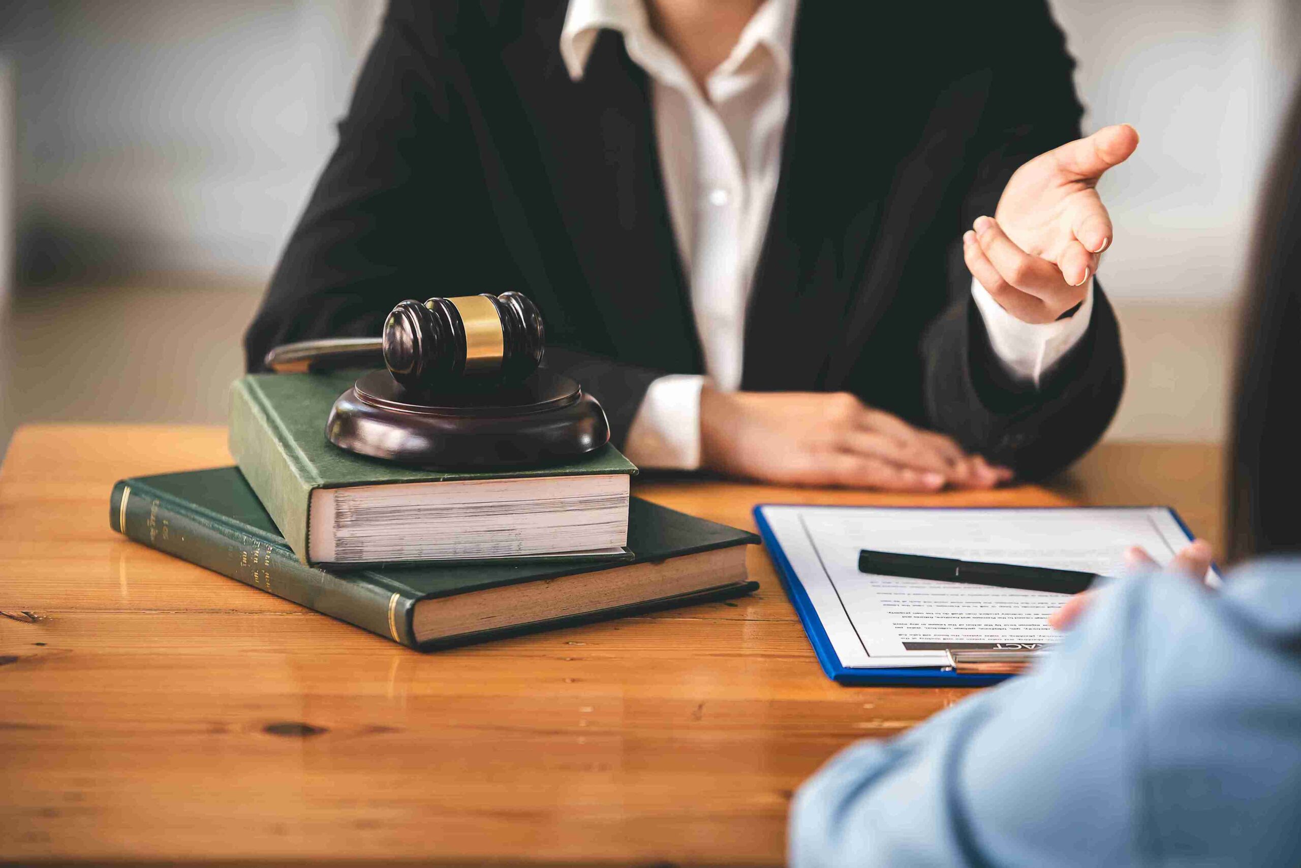 Elderly woman in professional attire consulting with a man at a desk, representing solicitors providing confident guidance to start the process.