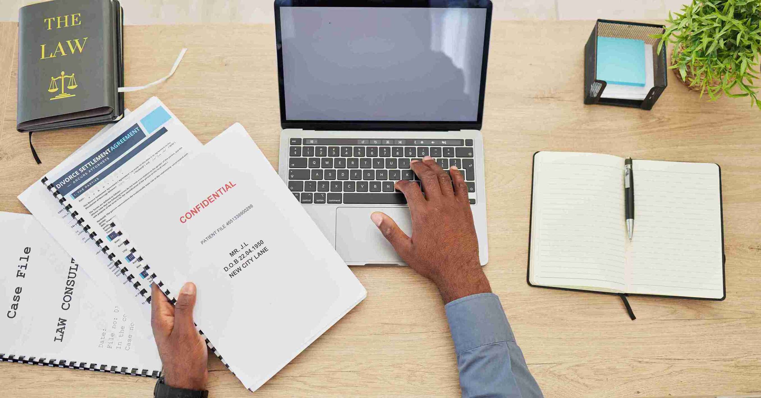 A person focused on a laptop, with a notebook open beside them, engaged in work or study.