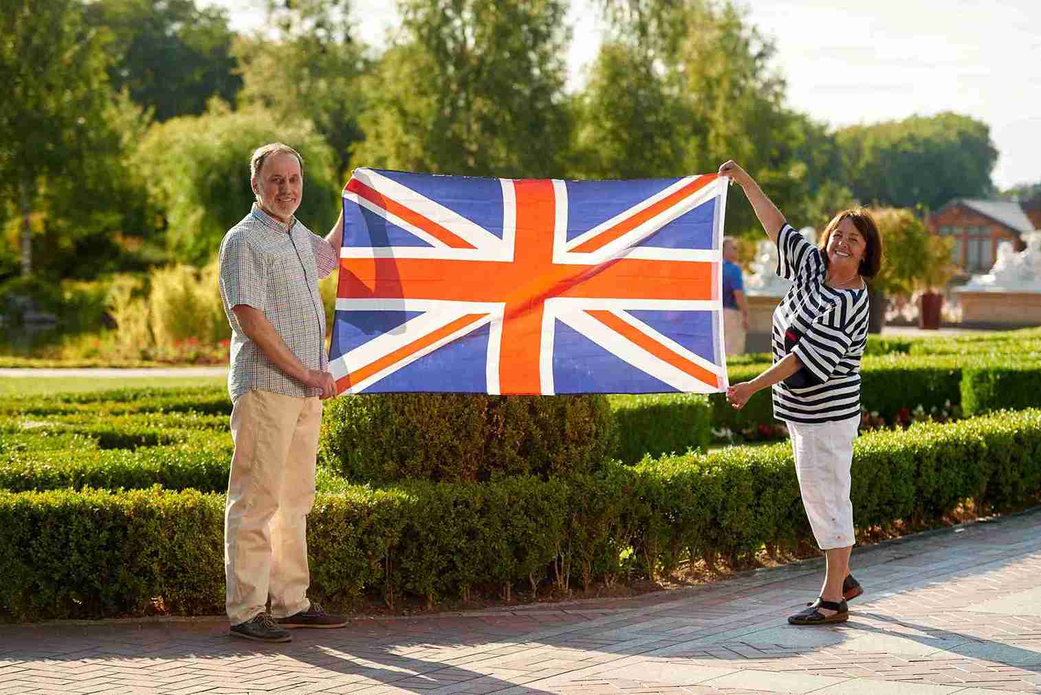 A man and woman proudly hold a British flag, smiling and celebrating together.