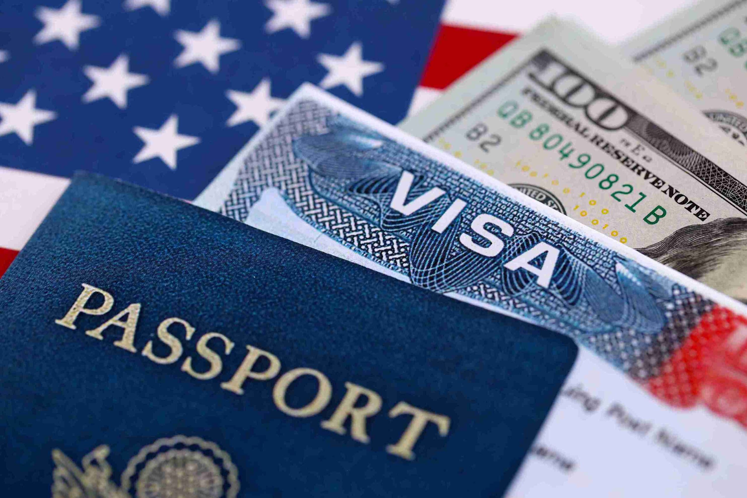 US visa and passport resting on an American flag, symbolizing travel and citizenship in the United States.
