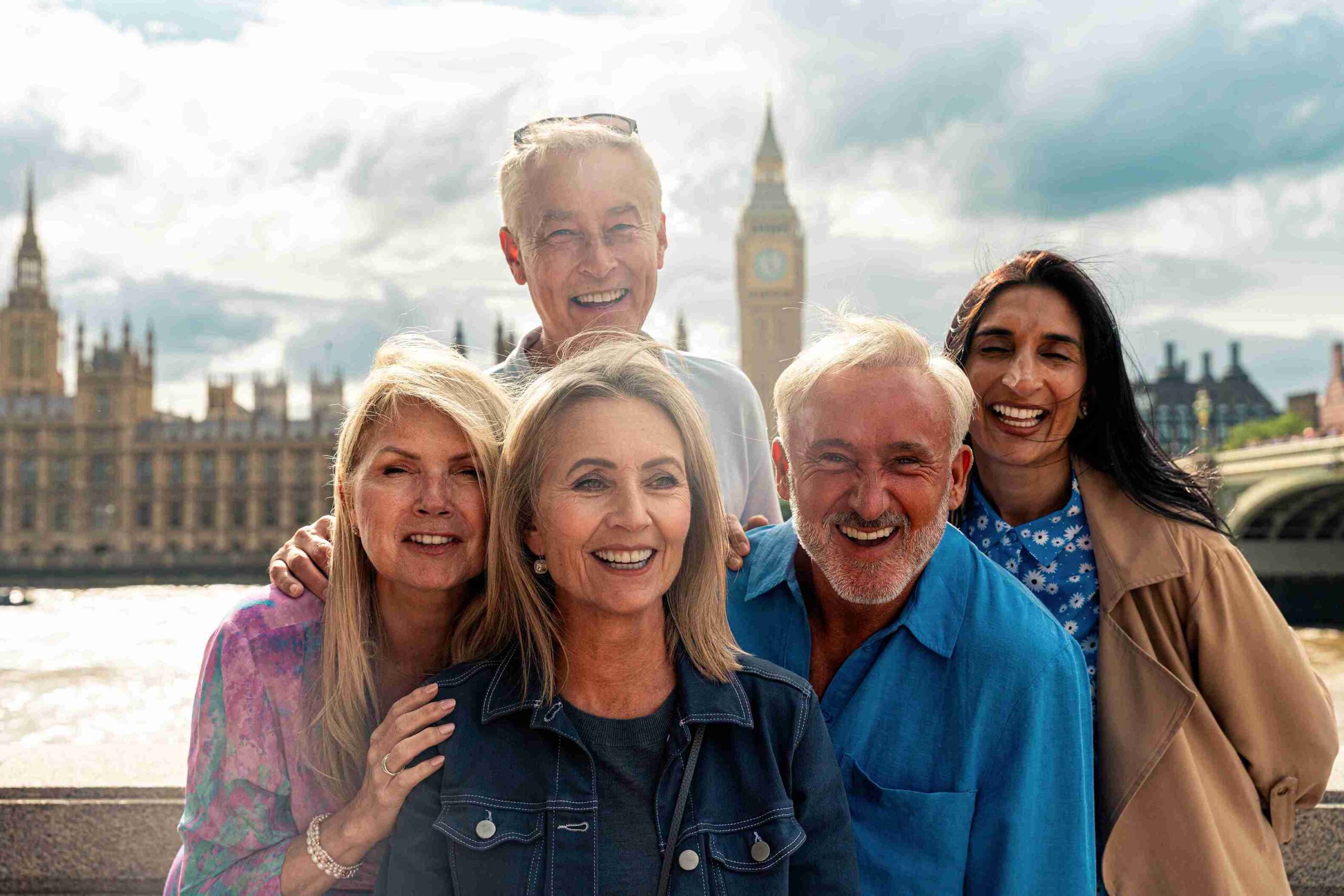 A group of older adults smiles for a photo in front of the iconic Big Ben clock tower in London.