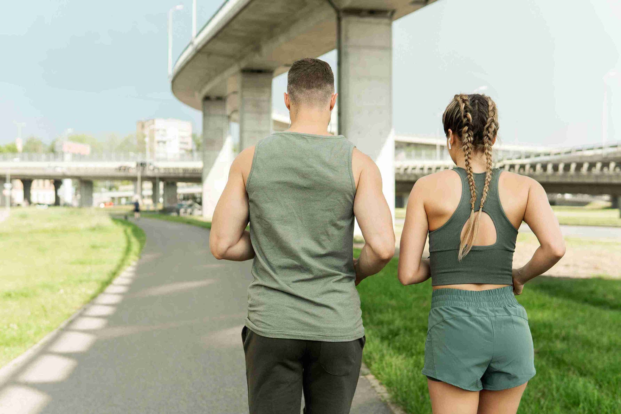 A man and woman stroll together along a scenic path surrounded by greenery.