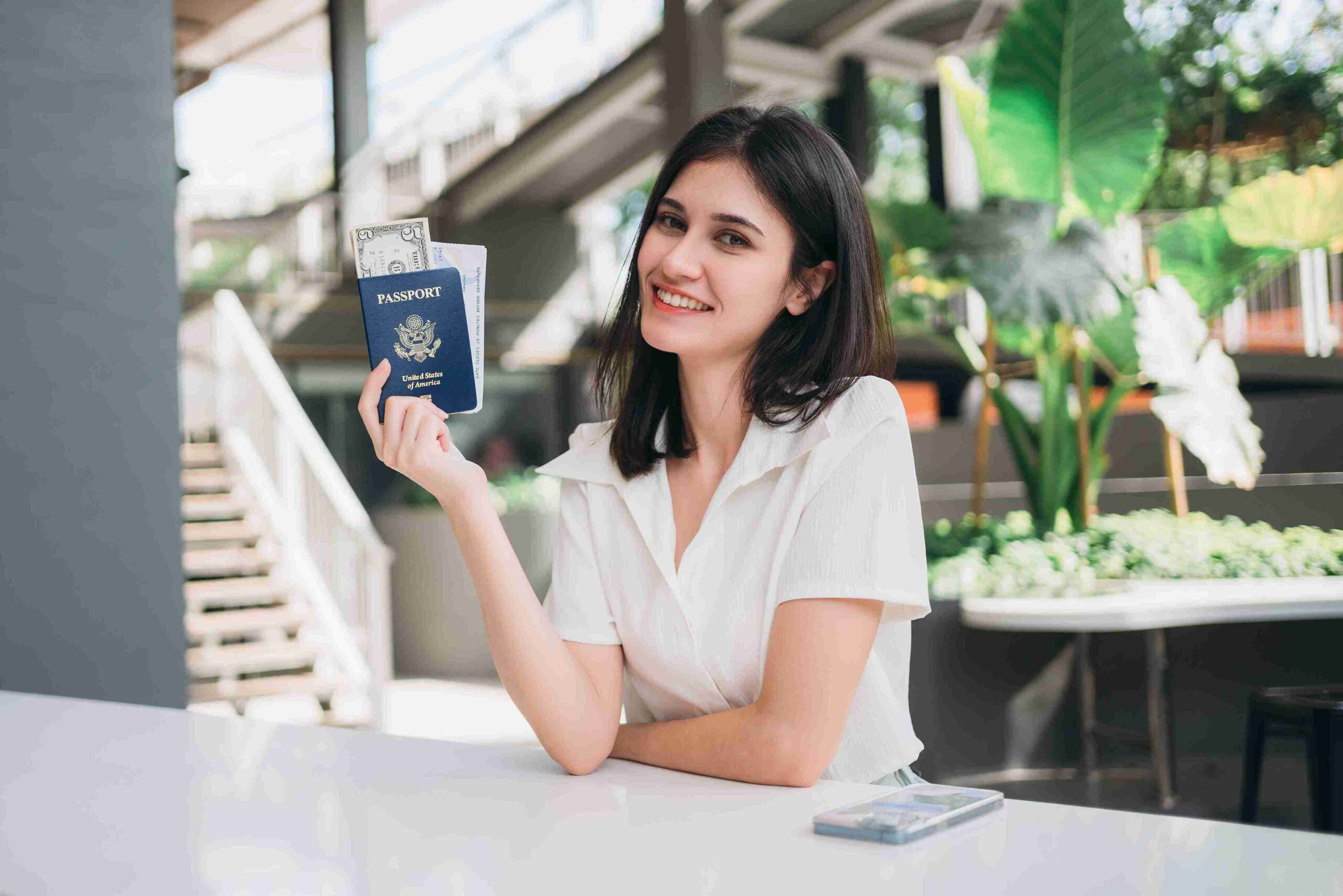 A smiling woman holds her passport, ready for her next adventure.